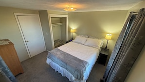 Een slaapkamer met een bed, twee nachtlampjes, een garderobe en een inloopkast.