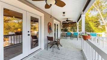 Eine überdachte Veranda mit Tisch und Stühlen, Deckenventilatoren und Blick ins Freie.