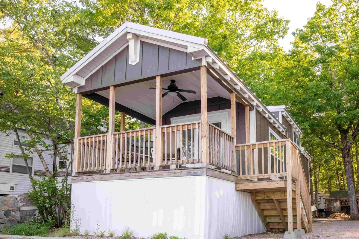 A wooden cabin with a covered porch and a small deck.