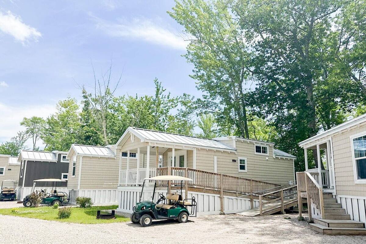 A row of mobile homes with a covered porch and a golf cart in the foreground.