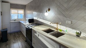 A modern kitchen with a herringbone-patterned backsplash, a stainless steel sink, and a gas stove. - Modern 2BR/2BA condo, upper floor, ocean breeze, short walk to Playa Chiquita (Sosúa)