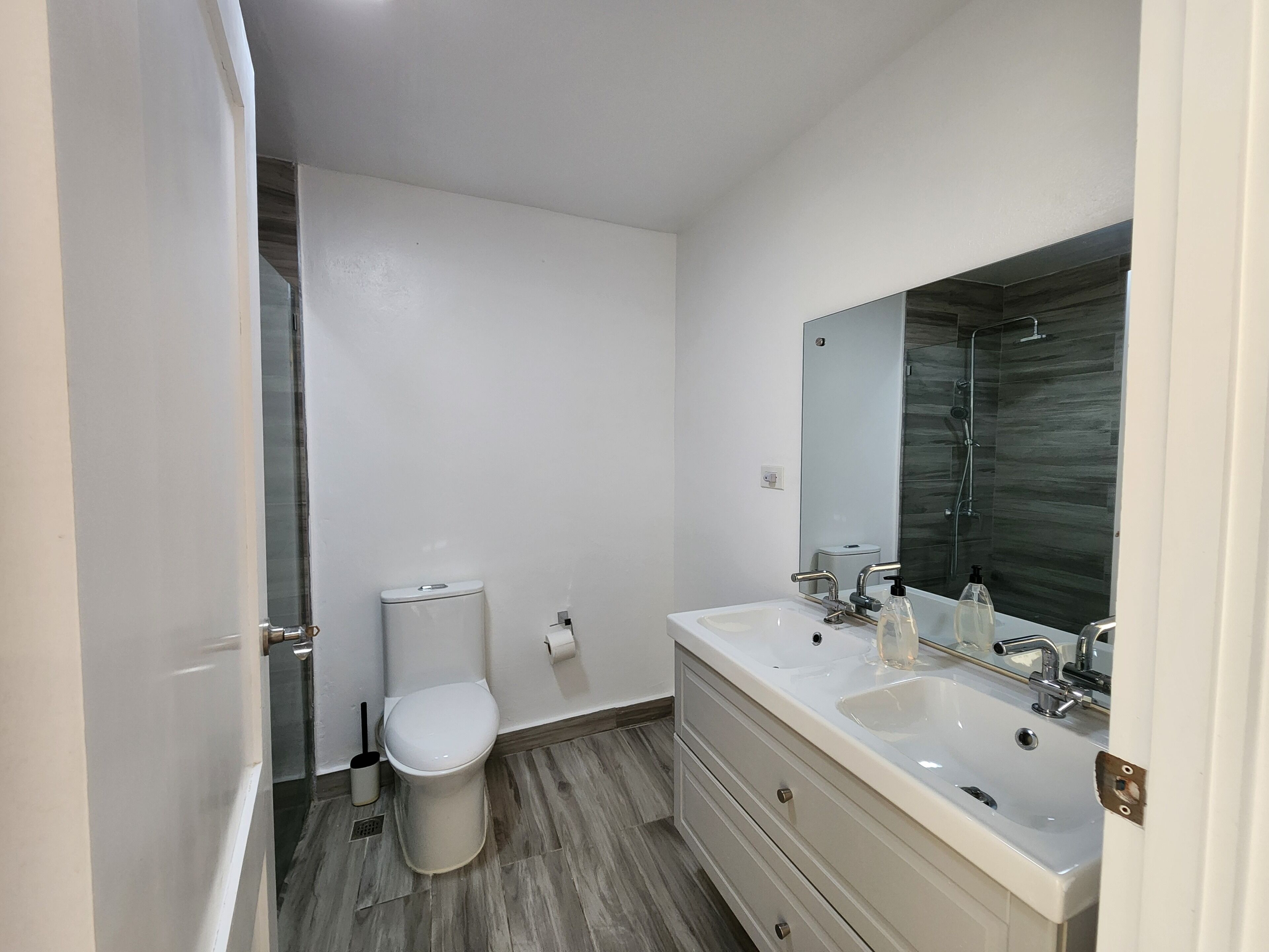 Een moderne badkamer met toilet, wastafel en spiegel.