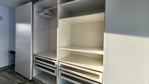 A walk-in closet with open shelves and a hanging rod. - Modern 2BR/2BA condo, upper floor, ocean breeze, short walk to Playa Chiquita (Sosúa)