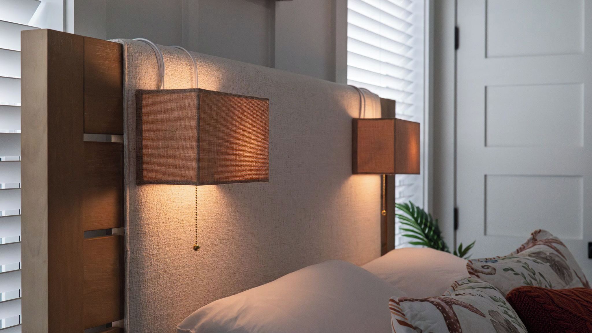 Ein modernes Schlafzimmer mit Kopfstütze, Nachttischlampen und einem Bett mit Kissen.