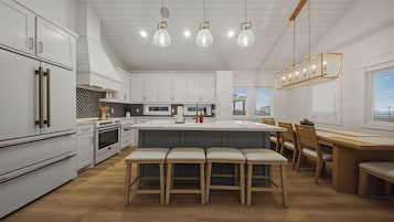 A modern kitchen with white cabinetry, a central island with stools, a dining area with wooden chairs, and pendant lighting.