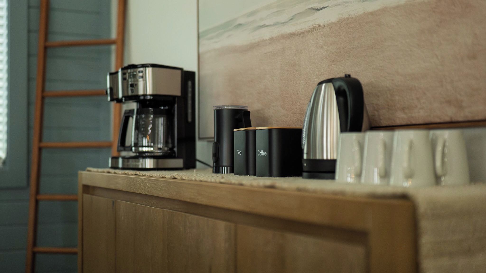 Un plan de travail de cuisine avec une machine à café, un récipient à thé et une cafetière.