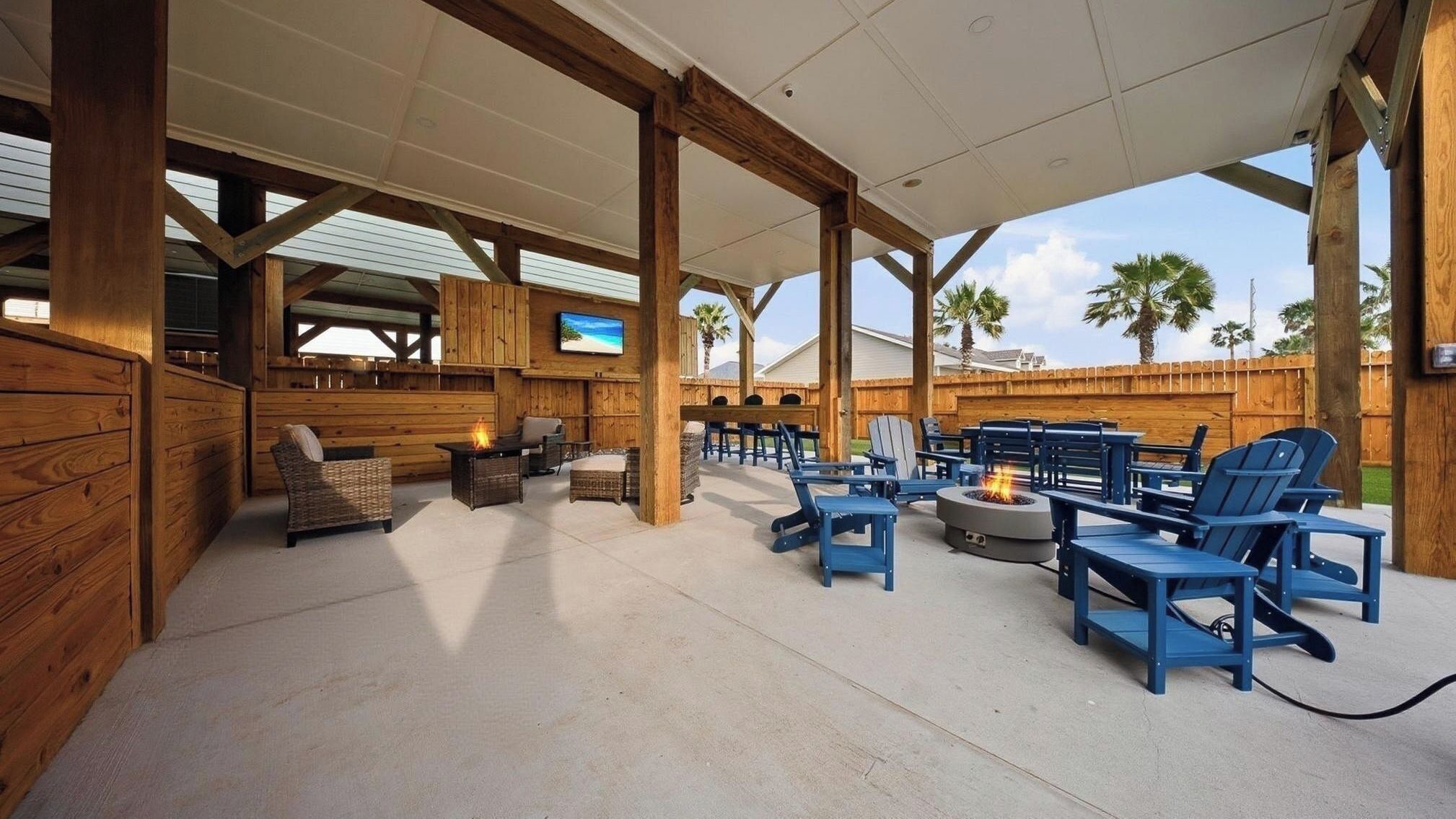 Une terrasse extérieure avec des poutres en bois, des meubles bleus et un foyer.
