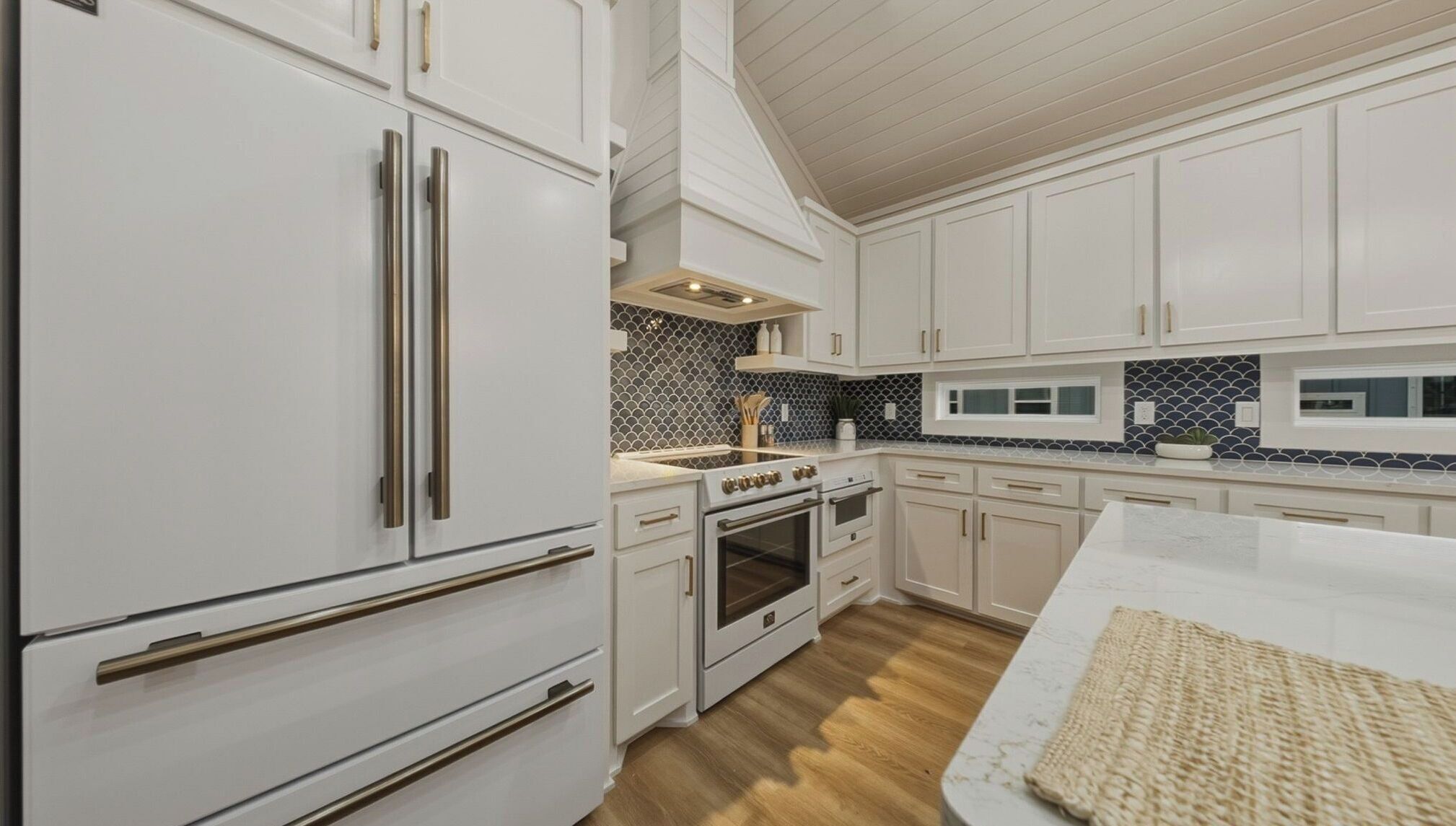 A kitchen with white cabinets, stainless steel appliances, and a patterned backsplash.