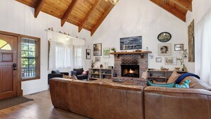 Uma sala de estar aconchegante com um sofá seccional grande, uma lareira e vigas de madeira no teto.