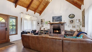 Ein gemütliches Wohnzimmer mit einem großen Ecksofa, einem Kamin und Holzbalken an der Decke.