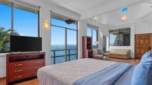 A spacious bedroom with a large bed, a TV, a wooden cabinet, a sofa, and a view of the sea. - With sea views / View Next to the Oxxo viewpoint (Mismaloya Aguacate)