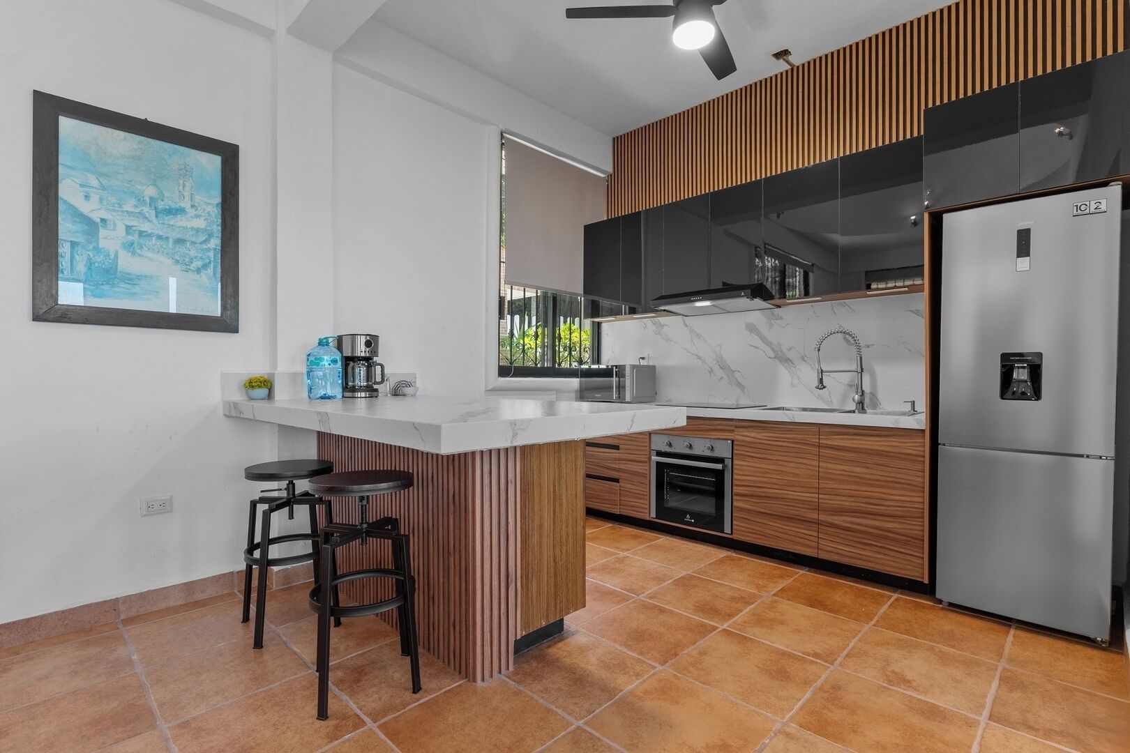A modern kitchen with a central island, built-in oven, and a refrigerator.