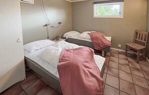 A room with two beds, a chair, a window, and a power outlet on the wall.