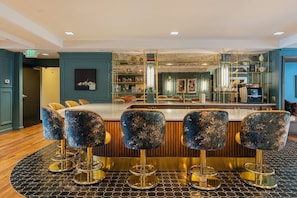Eine Bar mit einer zentralen Theke, Barhocker und einer Sitzecke mit Stühlen.