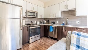 Une cuisine moderne dotée d’appareils électroménagers en acier inoxydable, de meubles en bois et d’un four encastré.