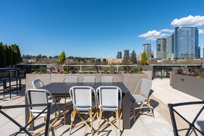 Une terrasse extérieure avec une table et des chaises, la silhouette de la ville en arrière-plan et une vue sur un parc.