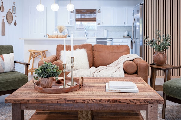Een gezellige woonkamer met een bruine bank, een houten salontafel en een groene fauteuil.
