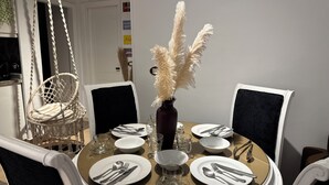 A round dining table with white chairs, a hanging chair, and a vase with pampas grass. - Brand New Boho Apartment Sharm (South Sinai Governorate)