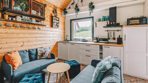 Een gezellig houten kamer in chaletstijl, met een kitchenette en een bank met kussens.