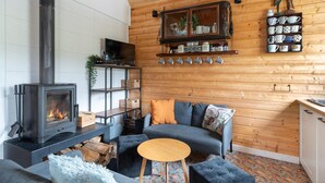 Een gezellige woonkamer met een open haard, een bank, een bijzettafeltje en een televisie.