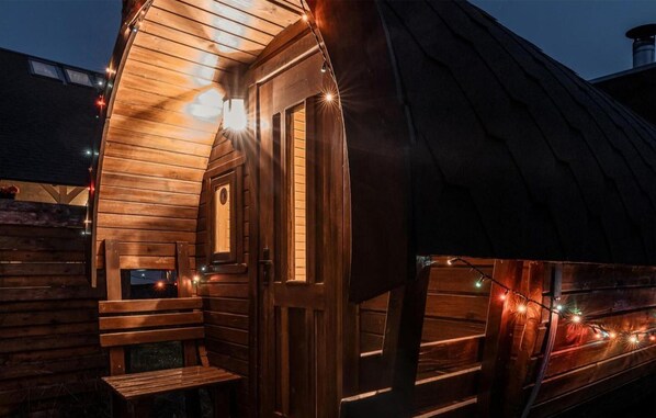 A wooden cabin with a sloped roof, a door, and a bench outside.