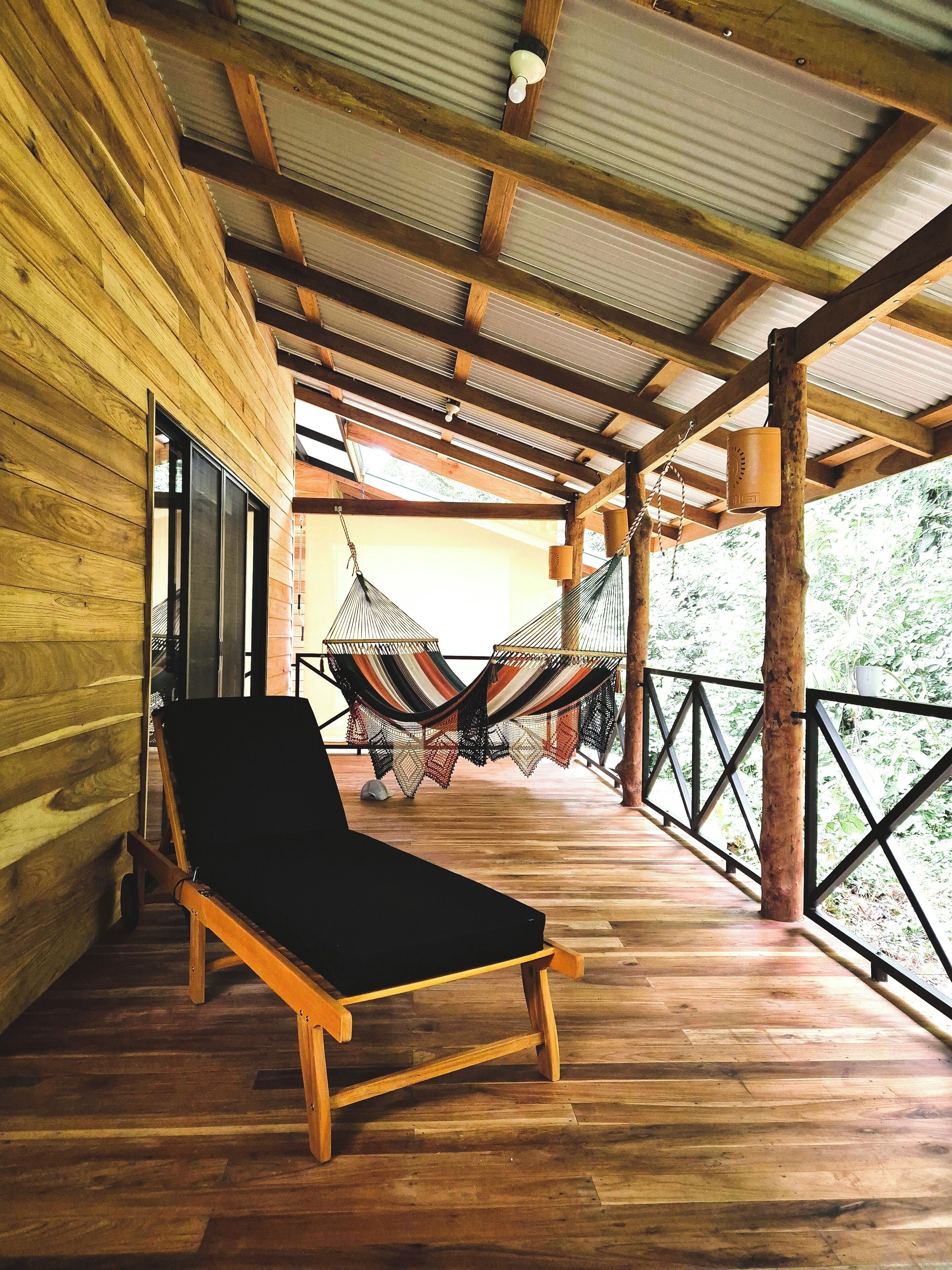 Una terraza de madera con una hamaca y un sillón de descanso.