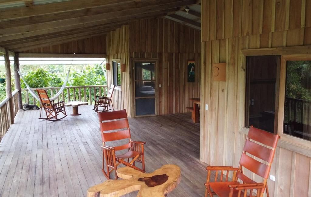 A wooden deck with rocking chairs and a table, overlooking a lush garden.