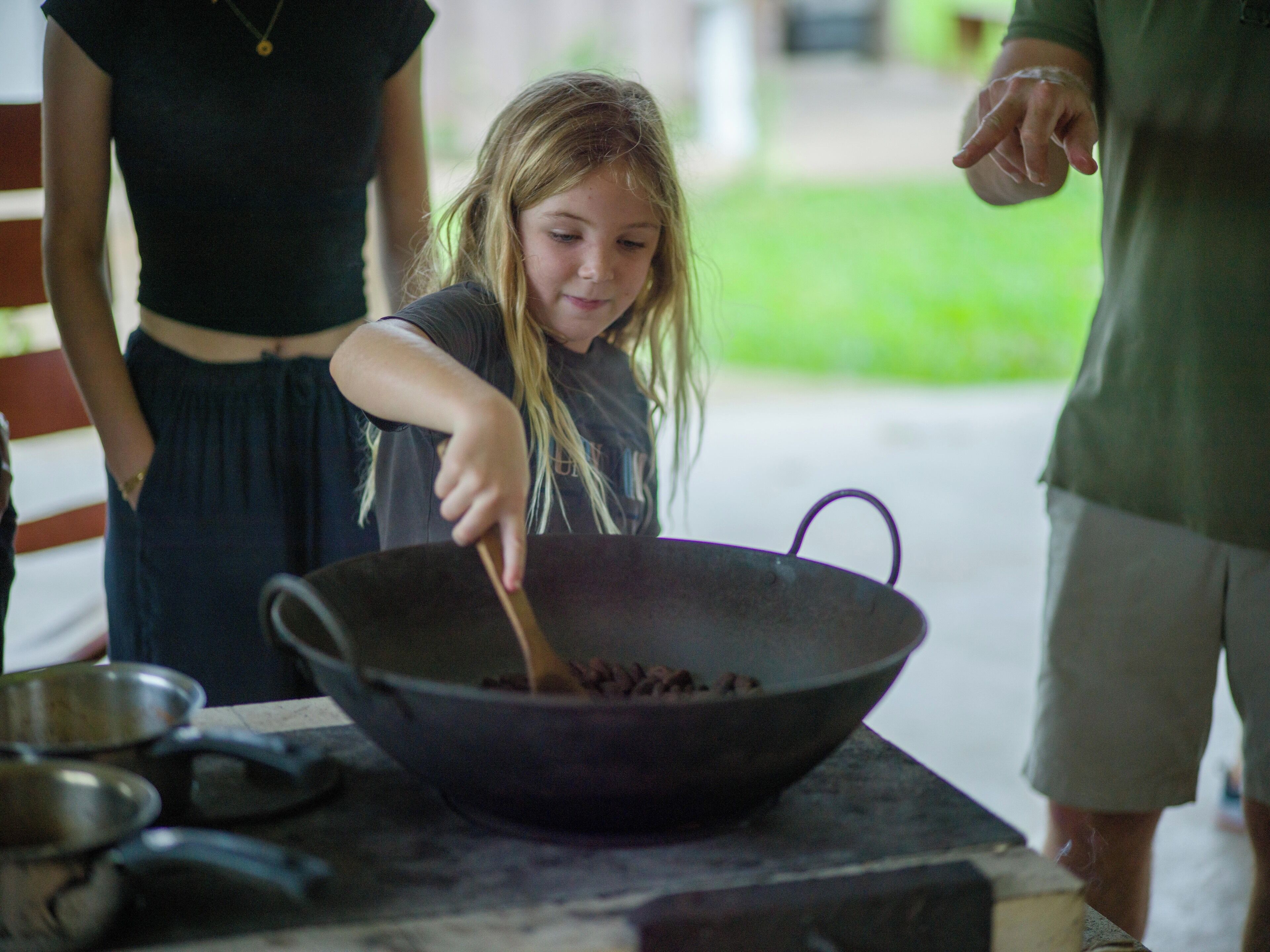 A person cooking in a large wok on an outdoor stove.