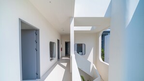 Un interior moderno con un pasillo largo, paredes blancas y ventanas amplias.