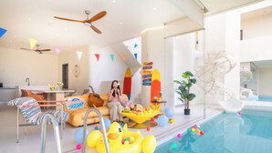 Un área de piscina interior moderna con un sofá, un patito inflable y una mesa de comedor.