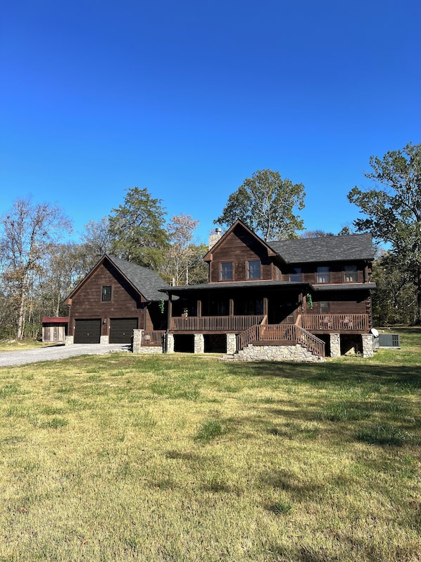 A two-story wooden house with a stone foundation, a covered front porch, and a garage.