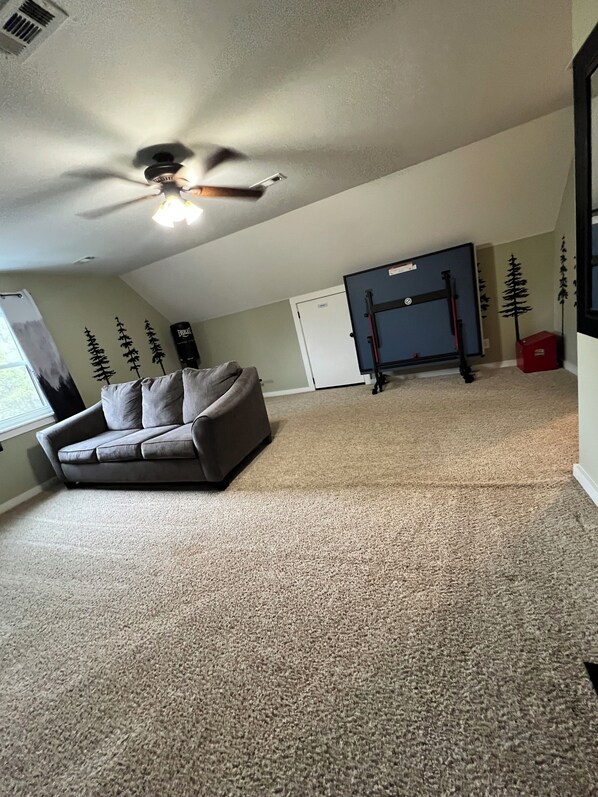 A room with a ceiling fan, a gray couch, a pull-up bar, and a door.