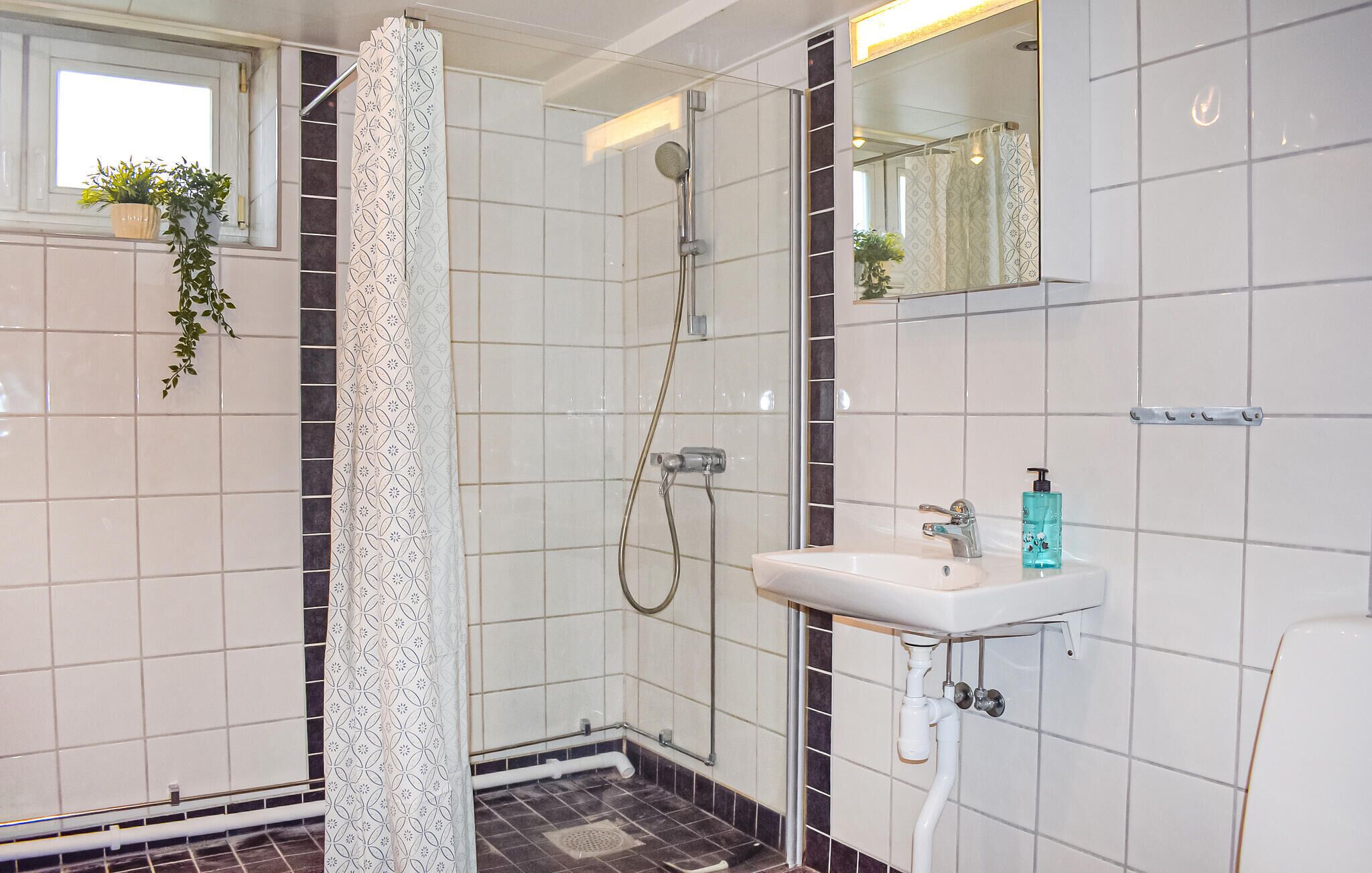 A bathroom with a shower, sink, and mirror.