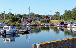 Ein Yachthafen mit mehreren vertäuten Booten, einer Brücke und roten Häusern im Hintergrund.
