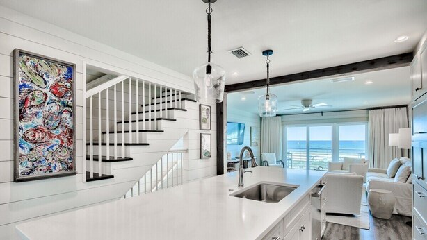 Una cocina moderna con encimera blanca, pileta de acero inoxidable y luces colgantes.