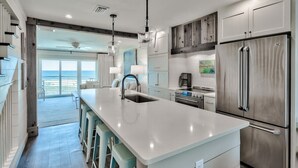 Cocina moderna con una isla grande, electrodomésticos de acero inoxidable y vistas al exterior.