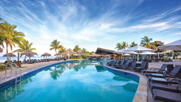 A swimming pool with lounge chairs and umbrellas, surrounded by palm trees and a clear sky. - Fiji -Wyndham- Beachfront Resort- Denarau - 3 BR (Nadi)