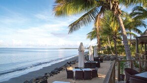 A beachfront restaurant with outdoor seating, palm trees, and a view of the ocean. - Fiji -Wyndham- Beachfront Resort- Denarau - 3 BR (Nadi)