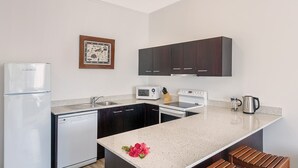 A compact kitchen with a refrigerator, microwave, stove, sink, and dark cabinets. - Fiji -Wyndham- Beachfront Resort- Denarau - 3 BR (Nadi)