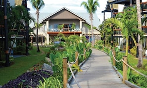 Ein Resort mit einem Hauptgebäude, einem Holzweg und tropischer Bepflanzung.