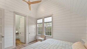 Un dormitorio con una cama grande, un ventilador de techo y una ventana con persianas.