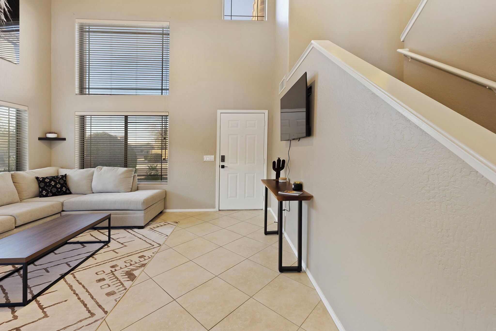 A modern living room with a sectional sofa, a coffee table, and a TV mounted on the wall.