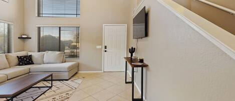 A modern living room with a sectional sofa, a coffee table, and a TV mounted on the wall.