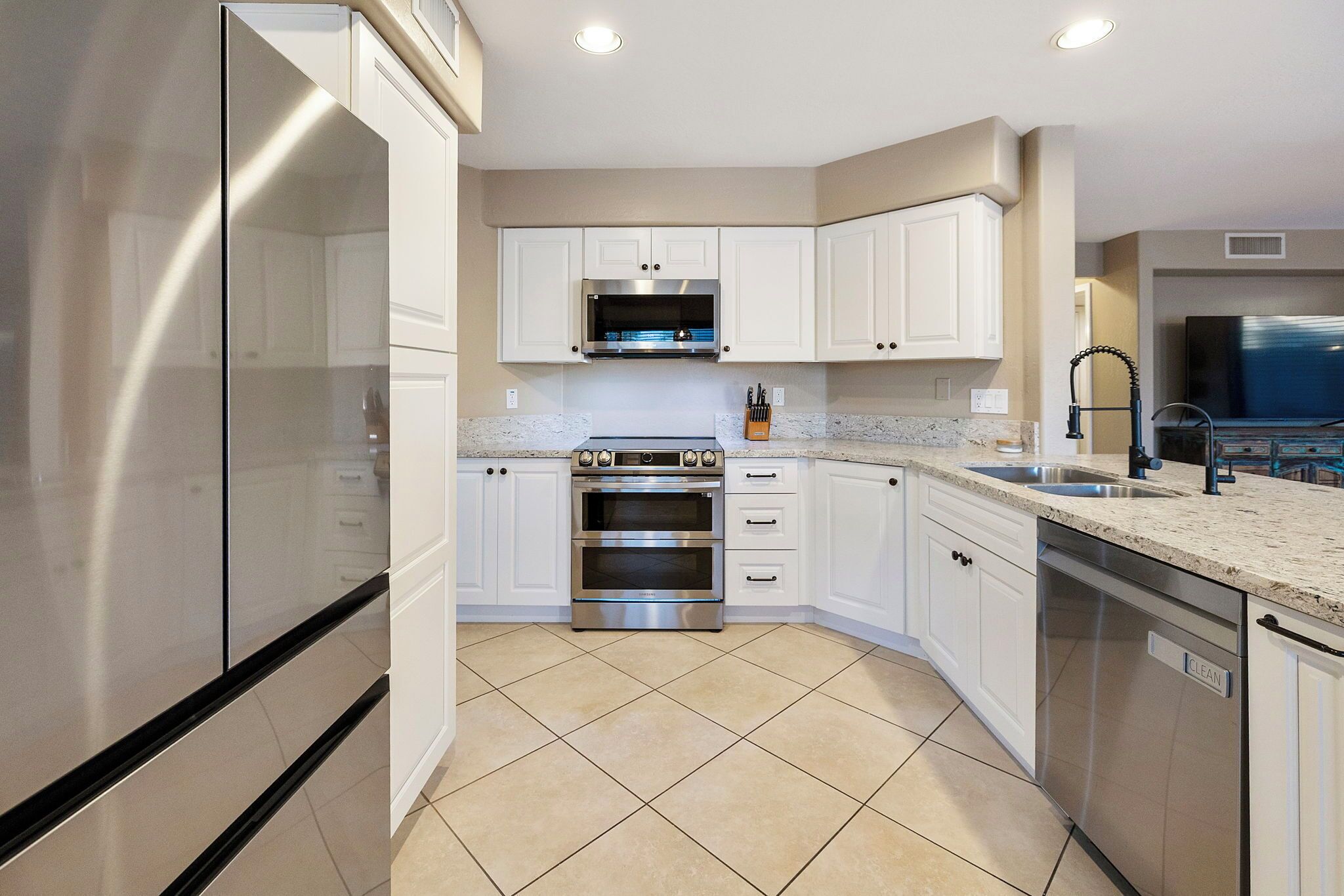 A modern kitchen with white cabinets, a stainless steel oven, and a dishwasher.