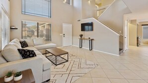 A spacious living room with a sofa, coffee table, and TV. A staircase leads to another level. - Tranquil Retreat in Cave Creek (Cave Creek)