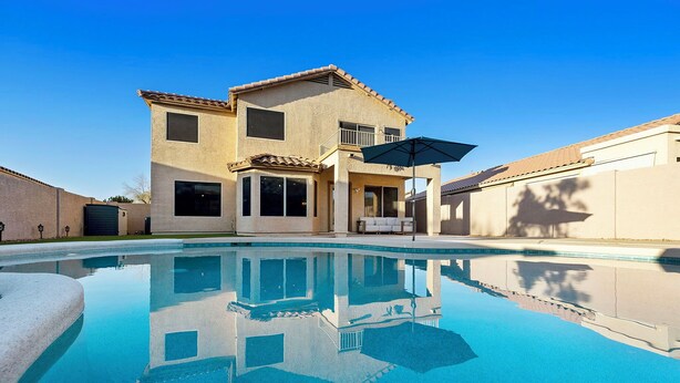 A two-story house with a swimming pool, a patio with a table and chairs, and a large umbrella. - Tranquil Retreat in Cave Creek (Cave Creek)