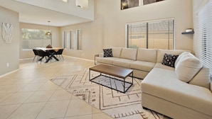 A spacious living area with a beige sofa, a coffee table, and a dining table with chairs. - Tranquil Retreat in Cave Creek (Cave Creek)