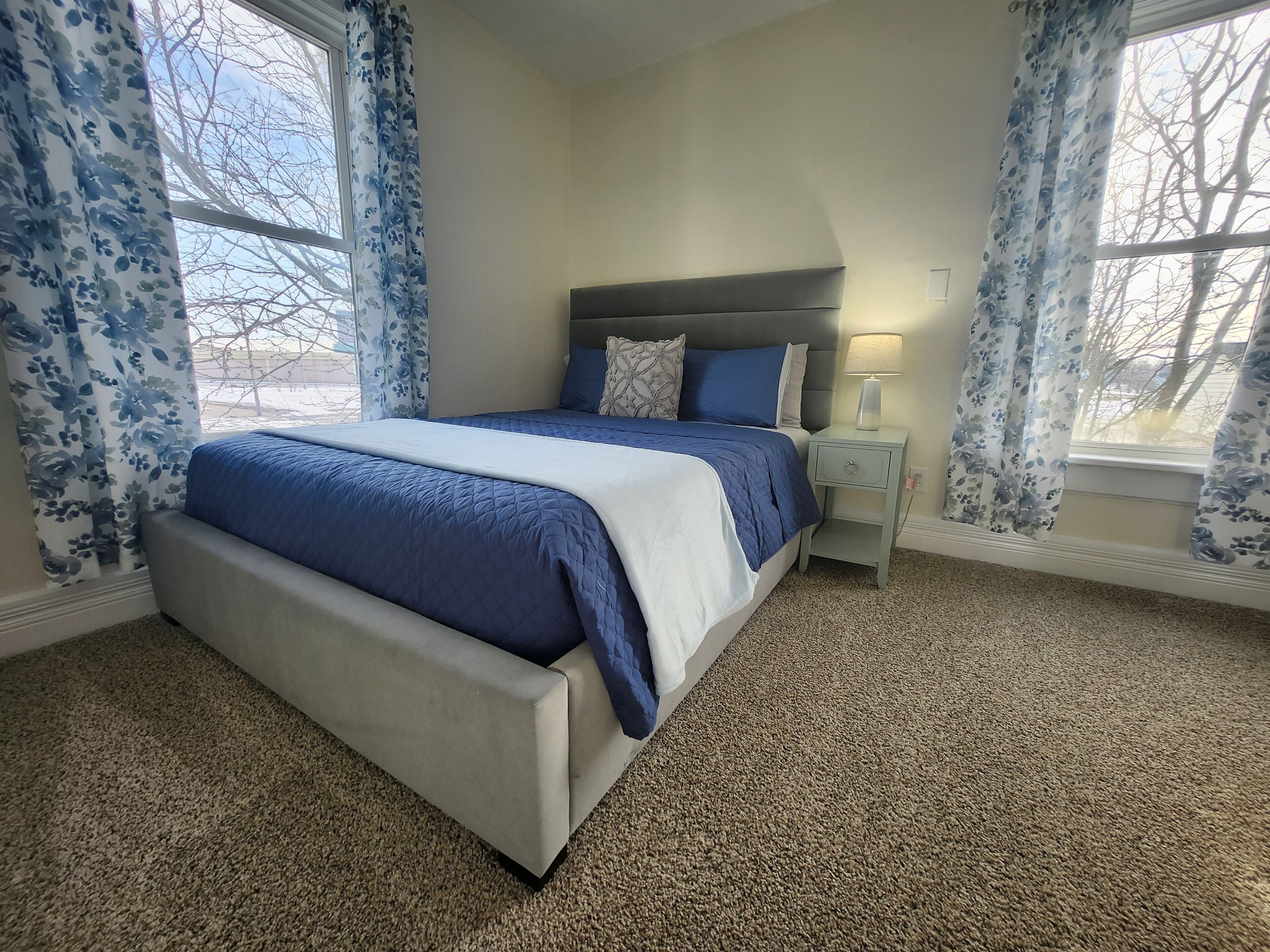 A bedroom with a bed, nightstand, and lamp.