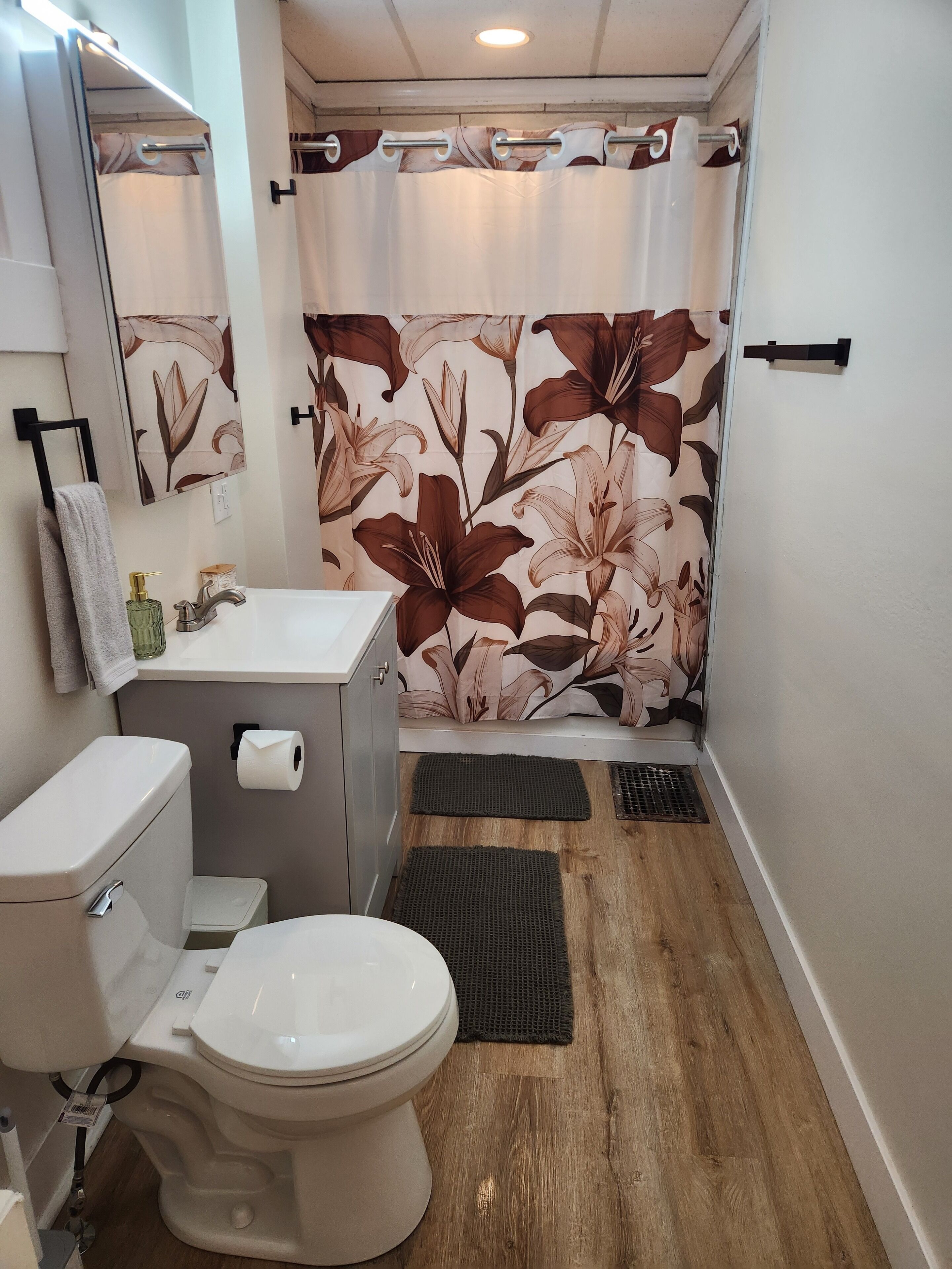 A bathroom with a toilet, sink, and shower curtain with a floral pattern.
