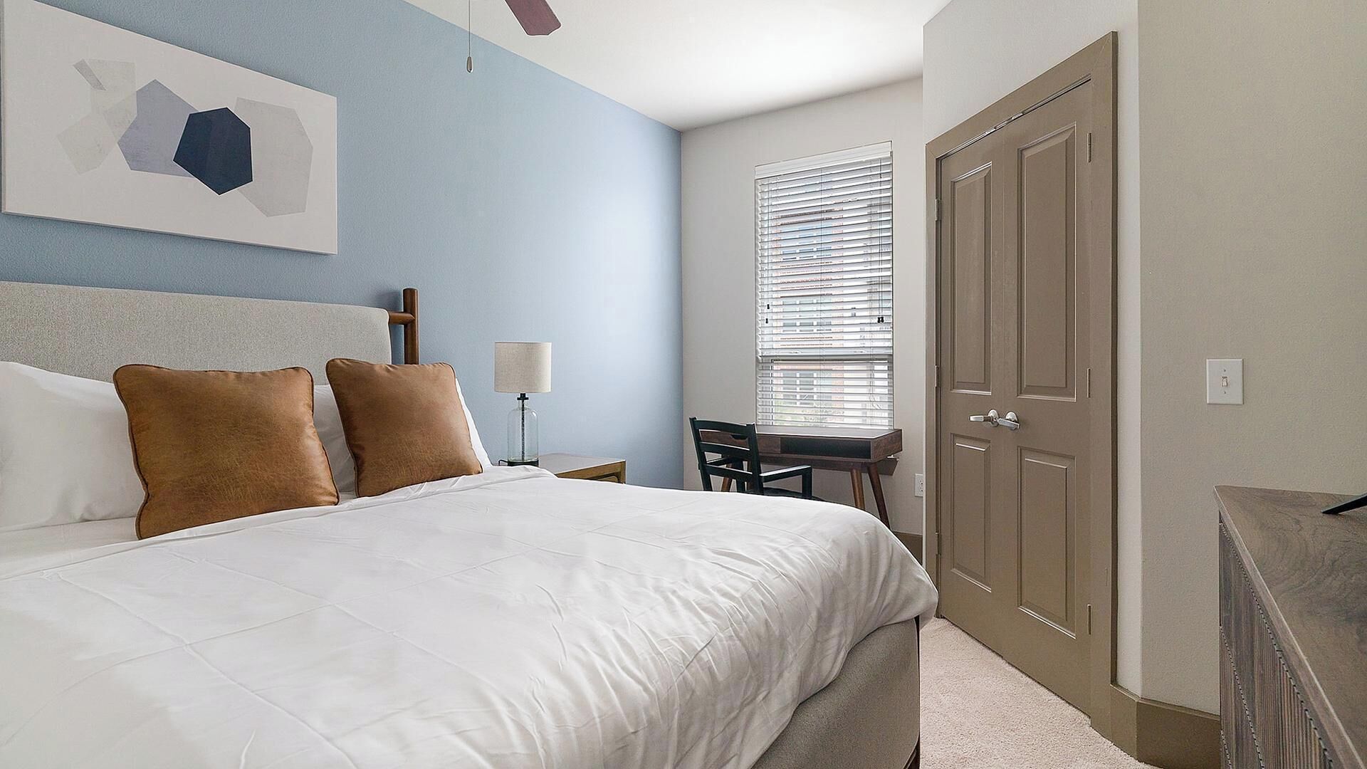A bedroom with a bed, a desk, and a wardrobe.